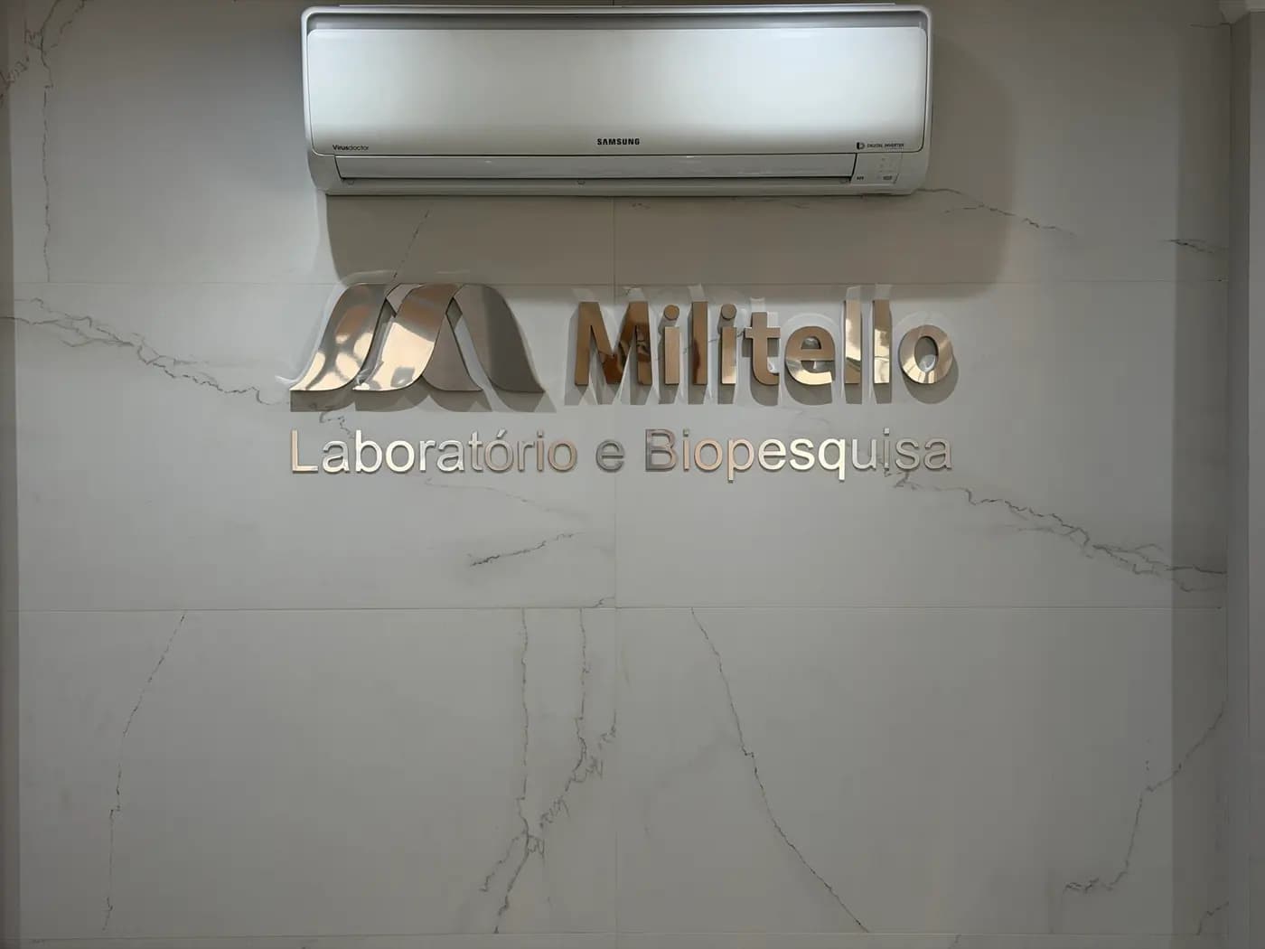 Letreiro "Militello — Laboratório e Biopesquisa" na parede de mármore da recepção